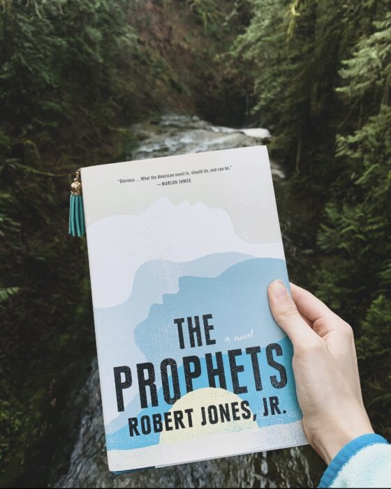 The Prophets being held up in front of river surrounded by trees