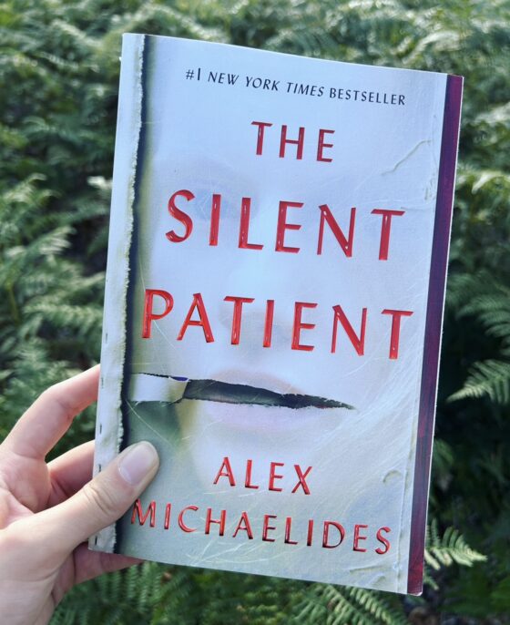 The Silent Patient held up in front of bush