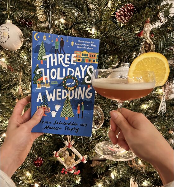 Three Holidays and a Wedding and Wedding Bell cocktail being held up in front of a Christmas tree.
