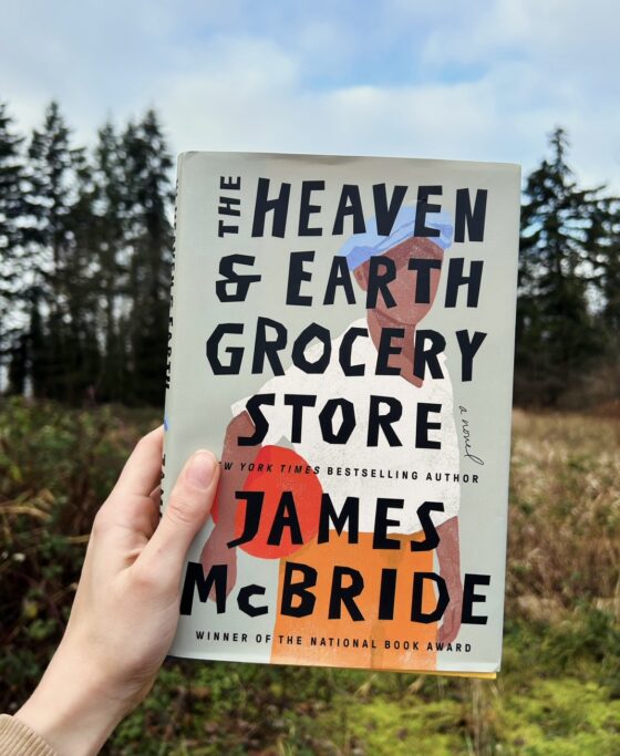 The Heaven and Earth Grocery Store held up in front of field with trees.