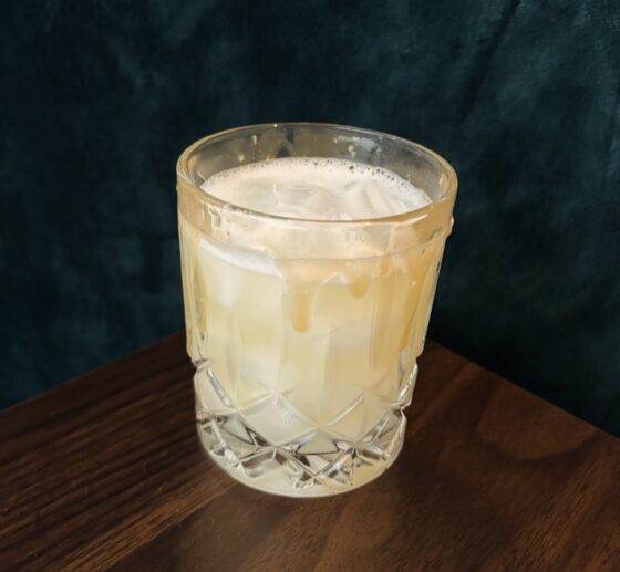 Cold Comfort cocktail on a wooden ledge with dark background