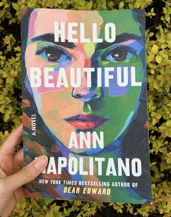 Hello Beautiful held up in front of yellow plant.